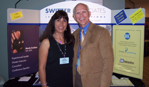Merlin and Nancy Switzer in front of a Switzer Associates booth